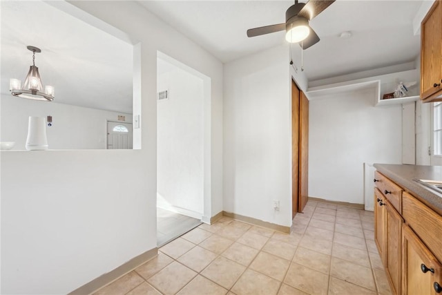 kitchen featuring light tile patterned flooring, pendant lighting, and ceiling fan with notable chandelier