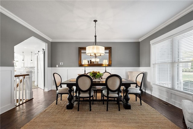 dining room featuring plenty of natural light, a barn door, and crown molding