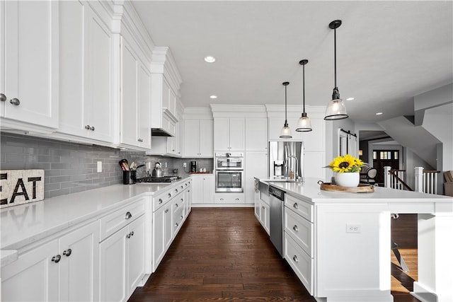 kitchen with pendant lighting, white cabinets, an island with sink, a kitchen bar, and stainless steel appliances