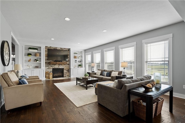 living room with dark hardwood / wood-style flooring, built in features, and a fireplace