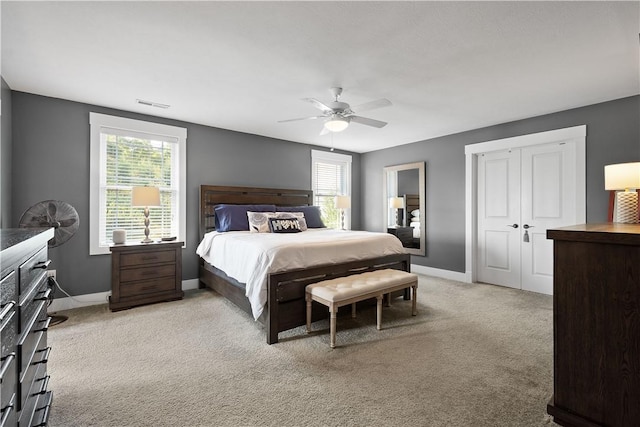 bedroom with multiple windows, ceiling fan, and light carpet