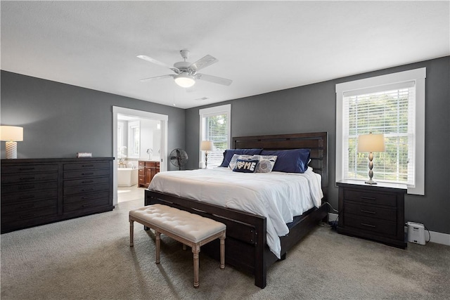 carpeted bedroom featuring ceiling fan, ensuite bathroom, and multiple windows