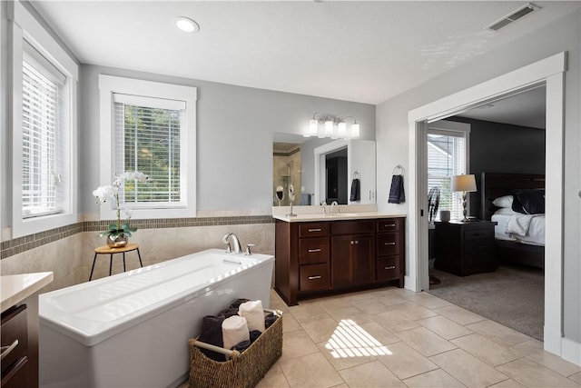 bathroom with tile patterned floors, vanity, a tub, and tile walls