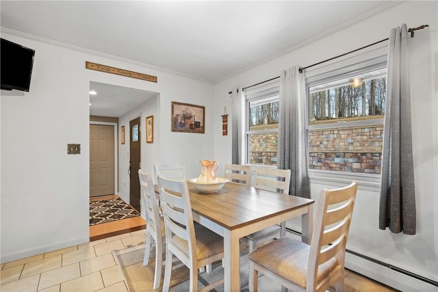 tiled dining space with baseboard heating and crown molding