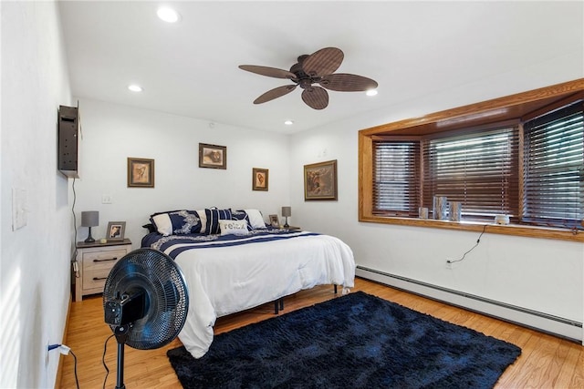 bedroom with light wood-type flooring, baseboard heating, and ceiling fan