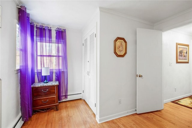 bedroom with ornamental molding, light hardwood / wood-style floors, and a baseboard heating unit