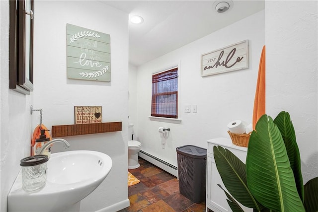 bathroom with sink, toilet, and a baseboard heating unit