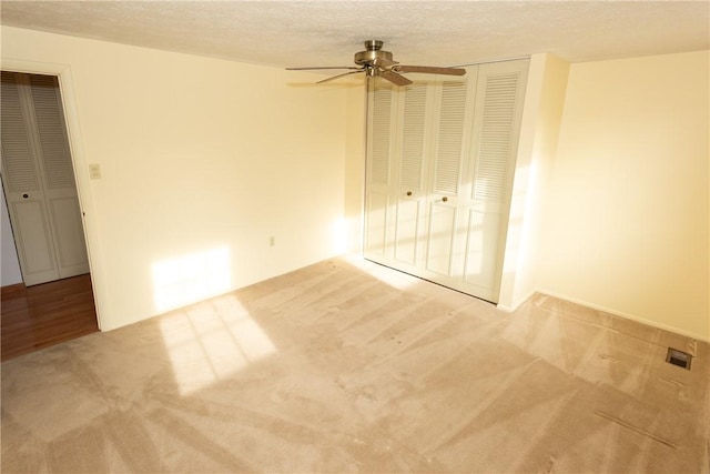 carpeted spare room with ceiling fan and a textured ceiling