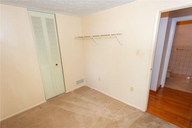 clothes washing area with light carpet and a textured ceiling