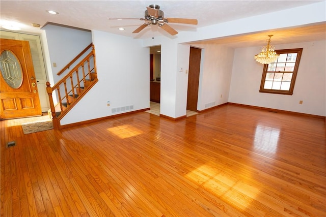 unfurnished living room with ceiling fan with notable chandelier and light wood-type flooring