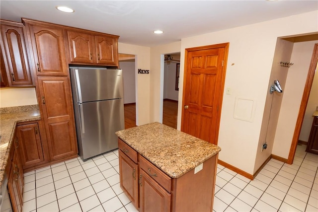 kitchen featuring light stone countertops, stainless steel fridge, and a center island