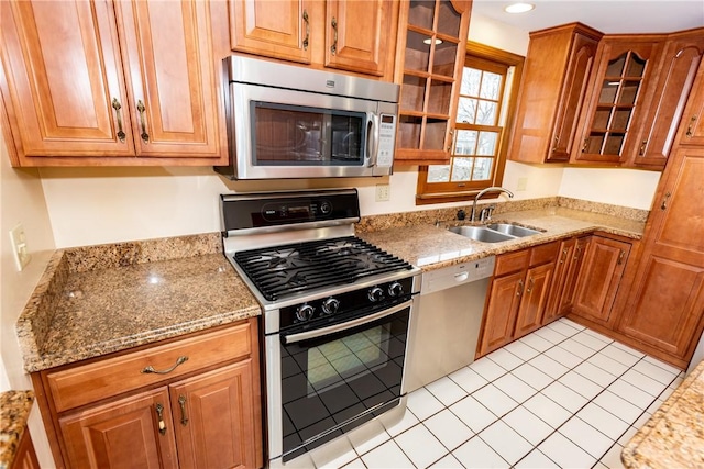 kitchen featuring light stone counters, sink, light tile patterned flooring, and stainless steel appliances