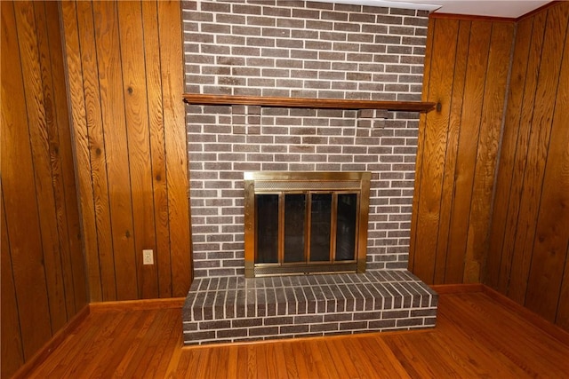 details featuring wood walls, hardwood / wood-style floors, and a brick fireplace