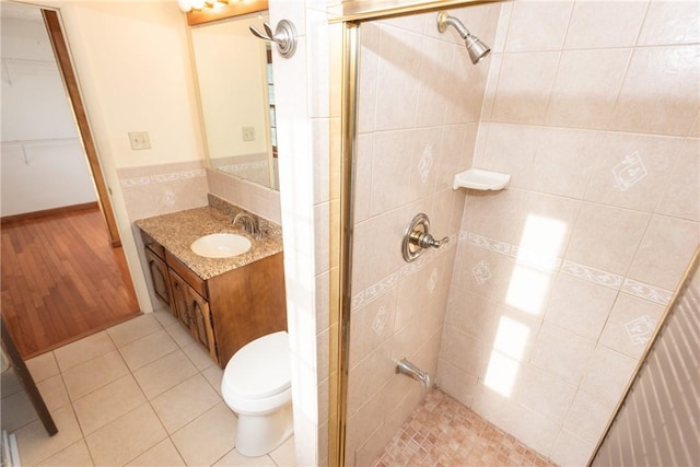 bathroom with tile patterned flooring, vanity, a shower with shower door, and toilet