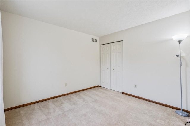 unfurnished bedroom with light carpet and a closet