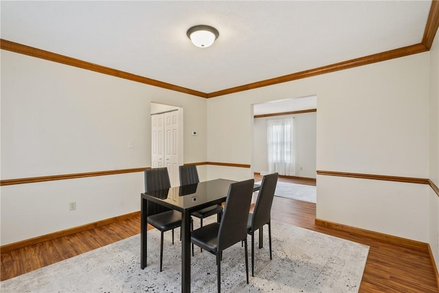 dining area featuring hardwood / wood-style floors and crown molding