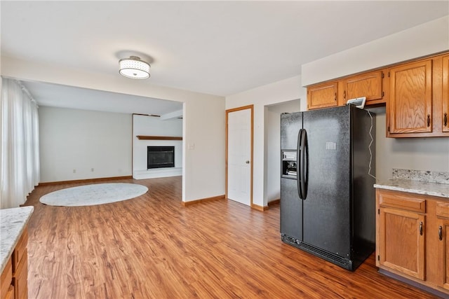 kitchen featuring black fridge, light hardwood / wood-style flooring, and light stone counters