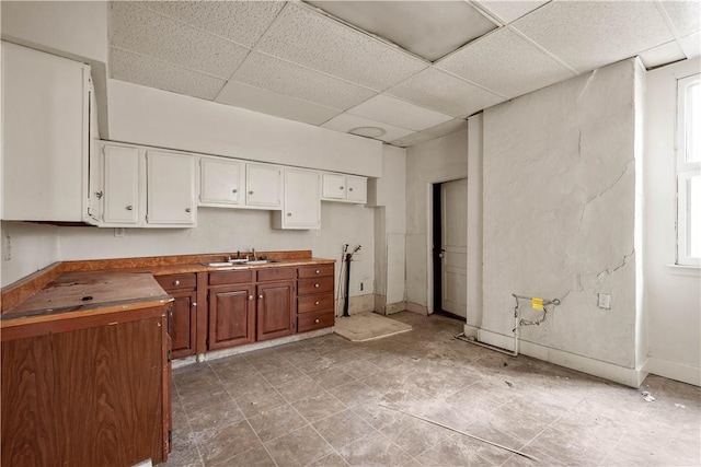 kitchen with white cabinets, a paneled ceiling, butcher block counters, and sink