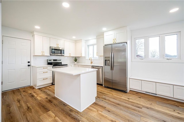 kitchen featuring tasteful backsplash, white cabinets, light hardwood / wood-style floors, and appliances with stainless steel finishes