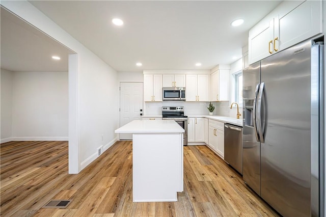 kitchen featuring appliances with stainless steel finishes, tasteful backsplash, sink, white cabinets, and a kitchen island