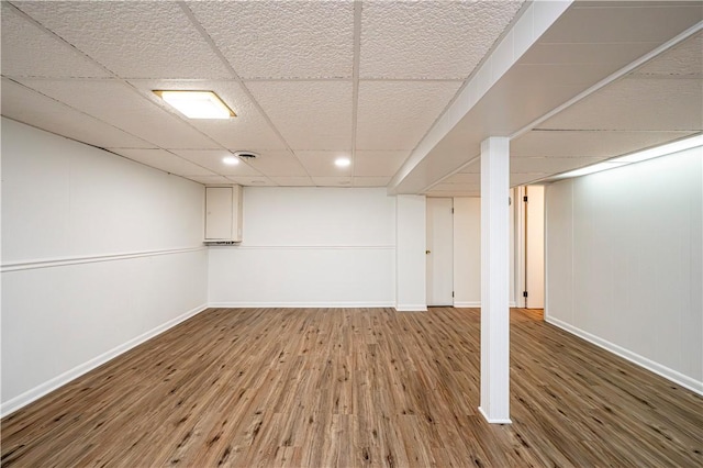 basement with wood-type flooring and a paneled ceiling