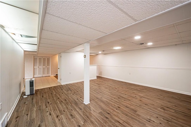 basement featuring hardwood / wood-style floors and a drop ceiling