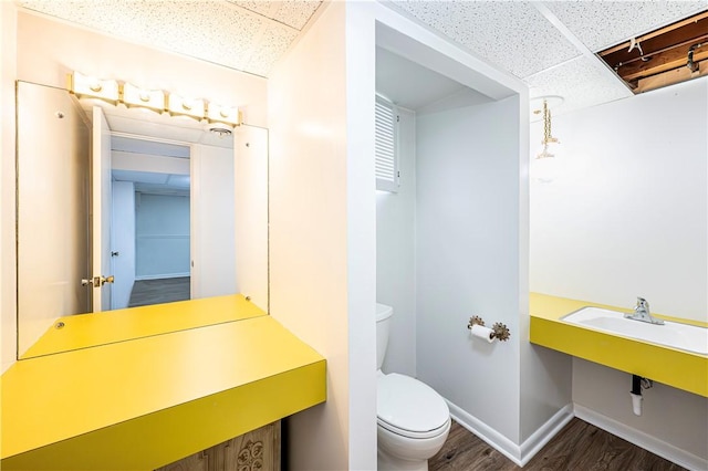 bathroom featuring hardwood / wood-style flooring, a drop ceiling, and toilet