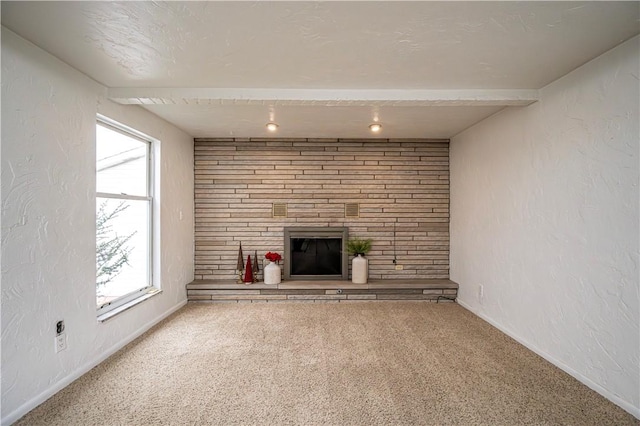 unfurnished living room with beamed ceiling, carpet flooring, and a fireplace