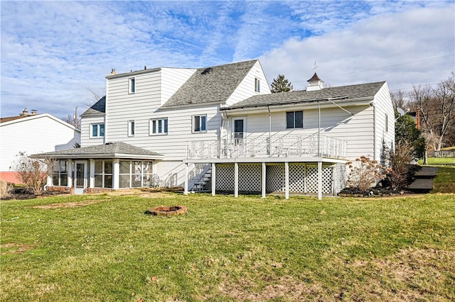 back of property with a yard, a wooden deck, and a sunroom