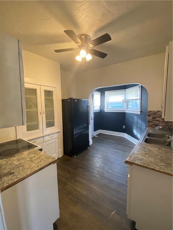 kitchen with dark wood-type flooring, black appliances, sink, ceiling fan, and white cabinetry