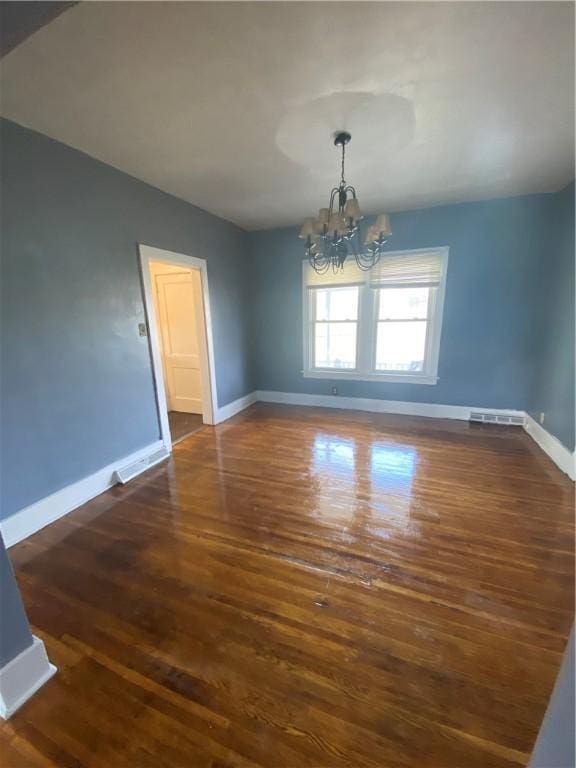 unfurnished dining area featuring dark wood-type flooring and an inviting chandelier