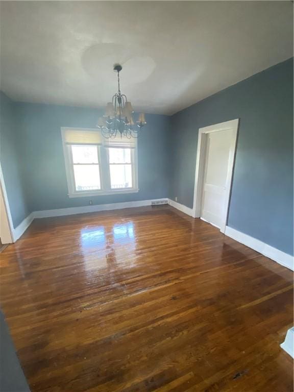 unfurnished dining area featuring dark wood-type flooring and an inviting chandelier