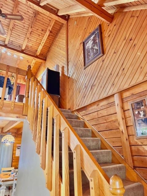 staircase featuring wood walls, beam ceiling, wood ceiling, and high vaulted ceiling