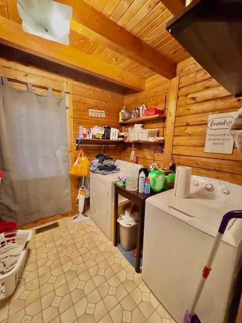 laundry room with washing machine and clothes dryer, rustic walls, and wood ceiling