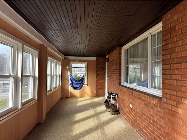 unfurnished sunroom featuring a healthy amount of sunlight and wooden ceiling