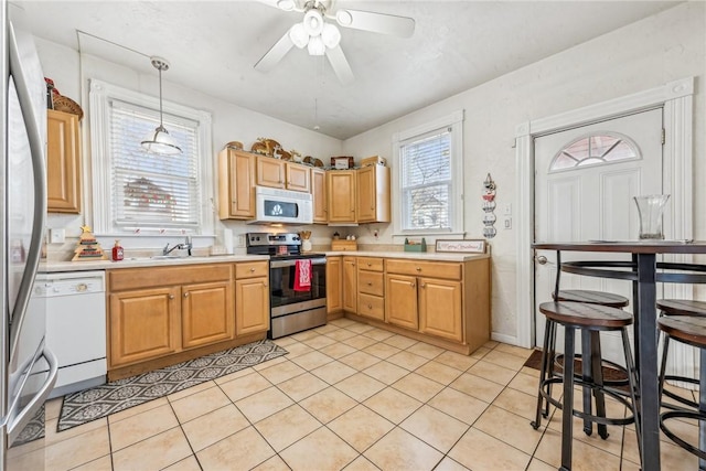 kitchen featuring appliances with stainless steel finishes, ceiling fan, sink, light tile patterned floors, and decorative light fixtures