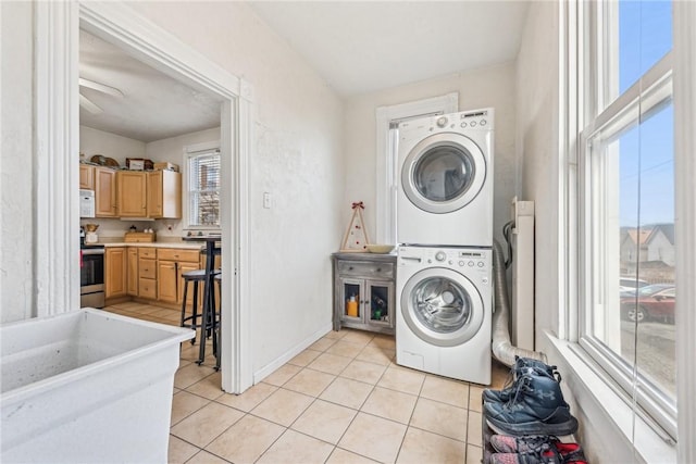 laundry area featuring light tile patterned floors and stacked washing maching and dryer