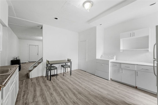 kitchen featuring white cabinets, washer / clothes dryer, and light hardwood / wood-style flooring