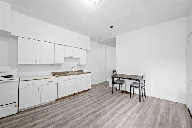 kitchen with stove, white cabinets, light hardwood / wood-style flooring, and sink