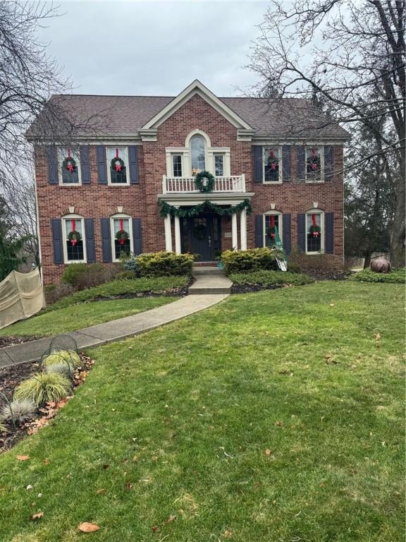 colonial home with a balcony and a front lawn