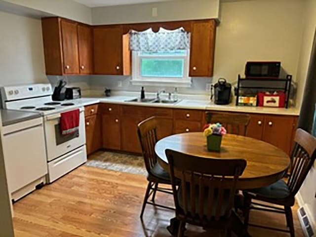 kitchen with electric range, sink, and light hardwood / wood-style floors