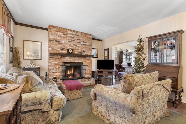 living room featuring dark colored carpet, crown molding, and a fireplace