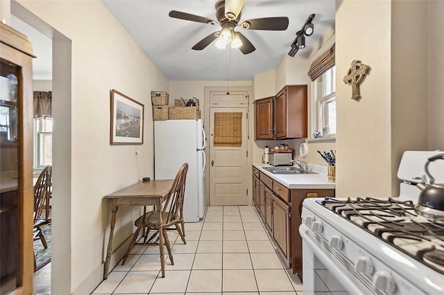 kitchen featuring a wealth of natural light, white appliances, ceiling fan, sink, and light tile patterned floors