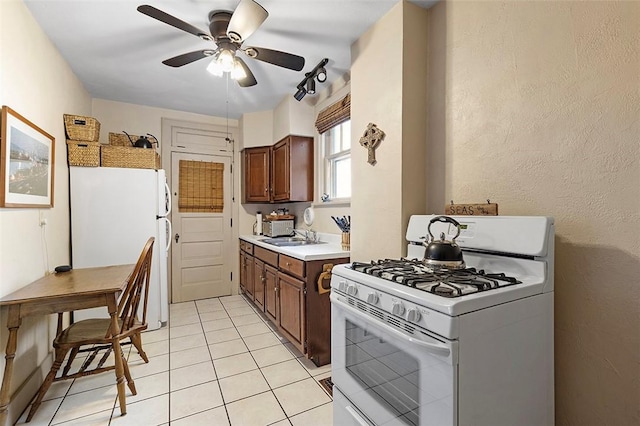 kitchen featuring white appliances, dark brown cabinetry, ceiling fan, sink, and light tile patterned floors