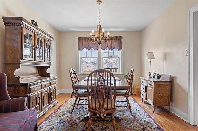 dining area with light hardwood / wood-style floors and an inviting chandelier