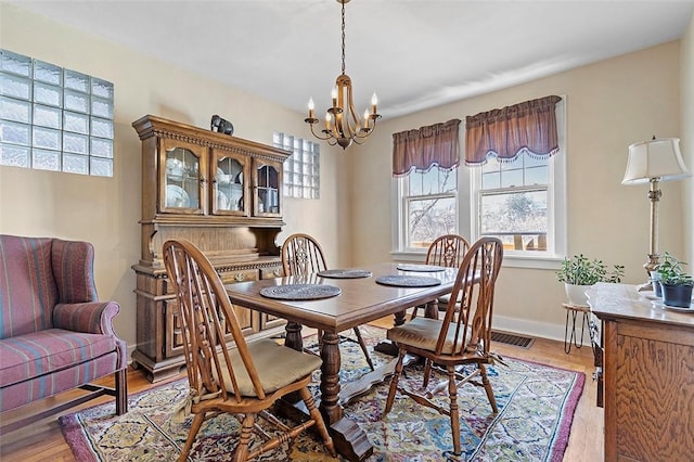 dining space featuring light wood-type flooring and a notable chandelier