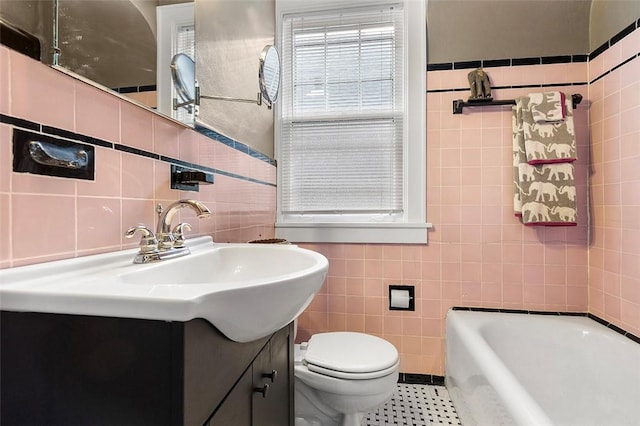 bathroom featuring a bathing tub, vanity, tile walls, and toilet