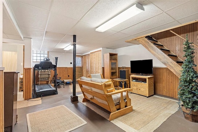 basement with a drop ceiling and wood walls