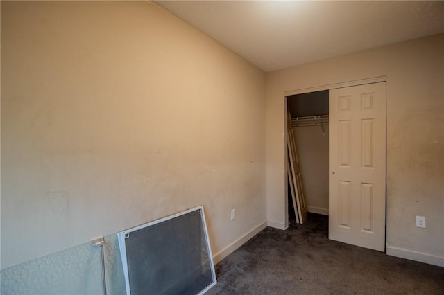 unfurnished bedroom with dark colored carpet and a closet