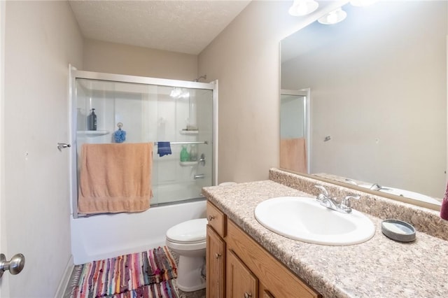 full bathroom featuring vanity, a textured ceiling, toilet, and combined bath / shower with glass door